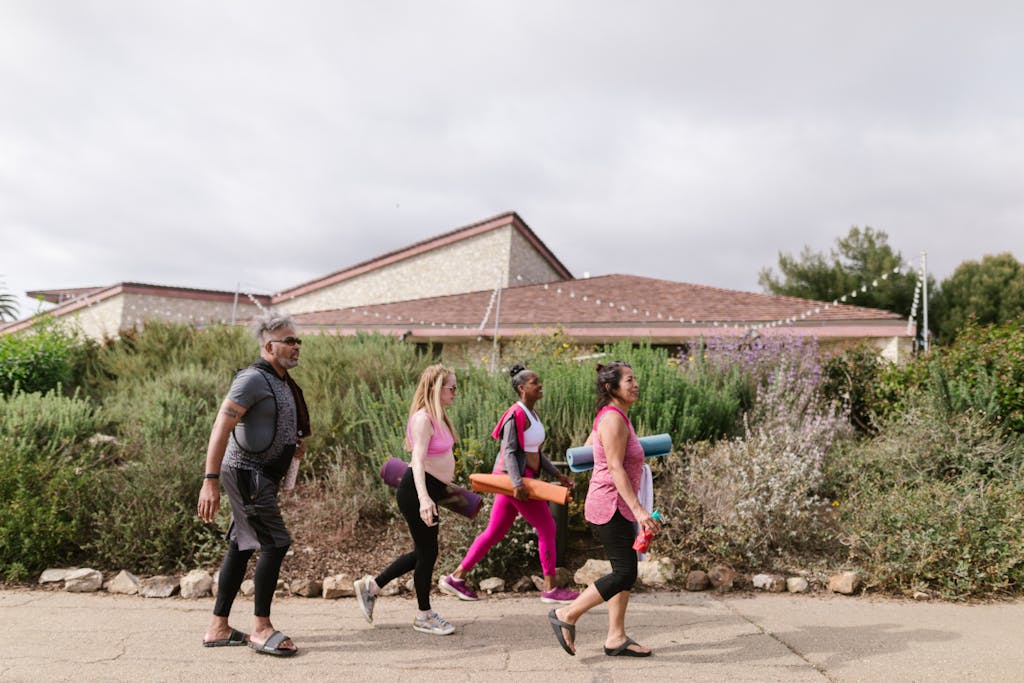 A group of adults carrying yoga mats walking outdoors, promoting health and active lifestyle.