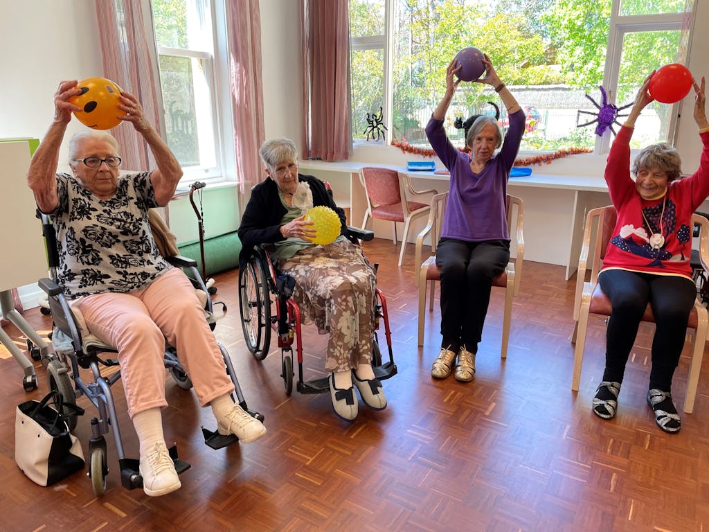 Elderly women engaging in fitness activities with exercise balls in a community center.