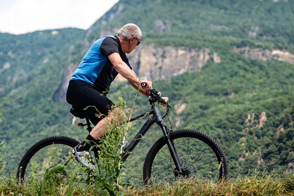 Senior man biking through scenic mountain landscape on a summer day.