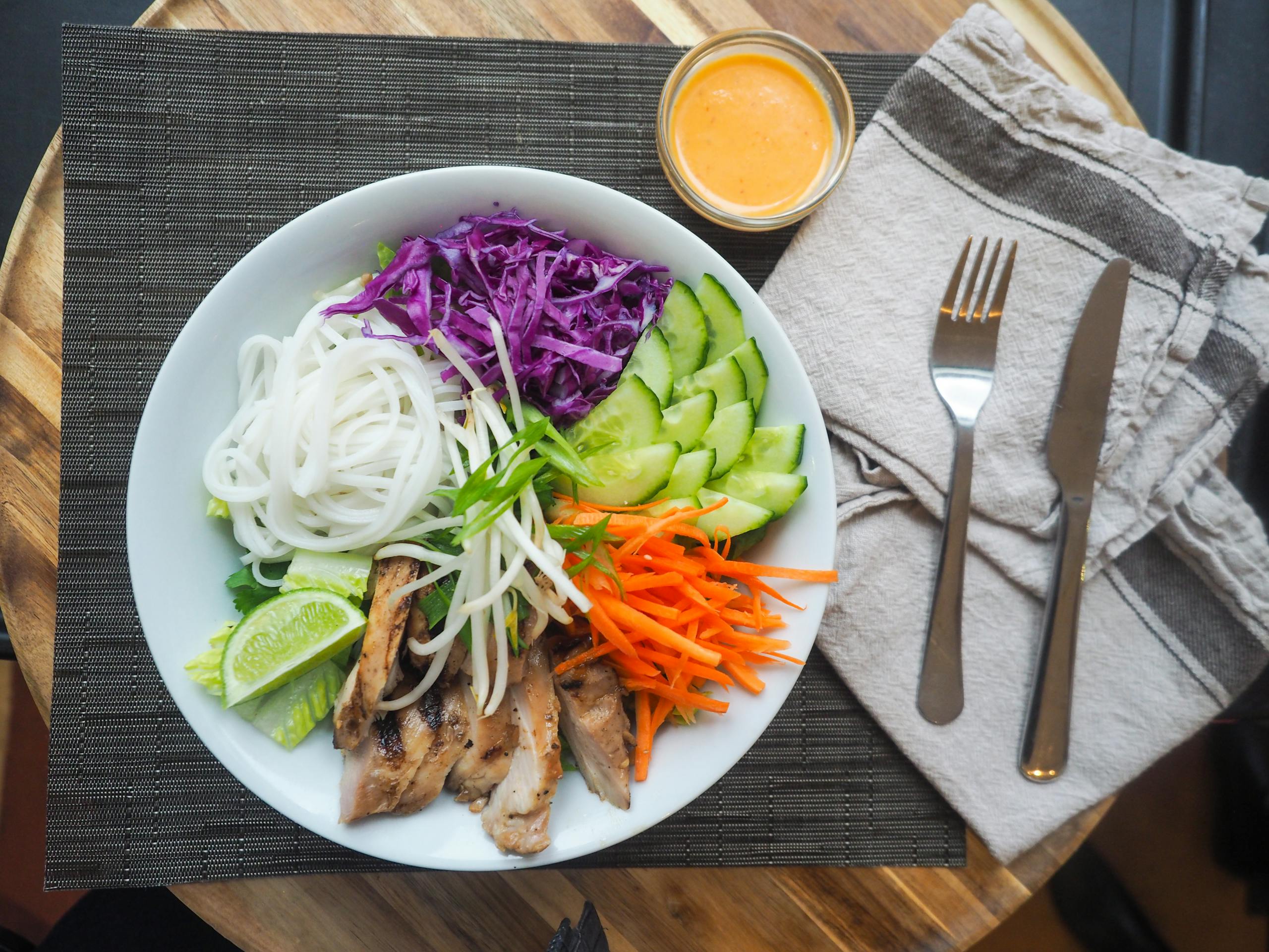 Vibrant Vietnamese noodle bowl with chicken, fresh vegetables, and spicy dressing.